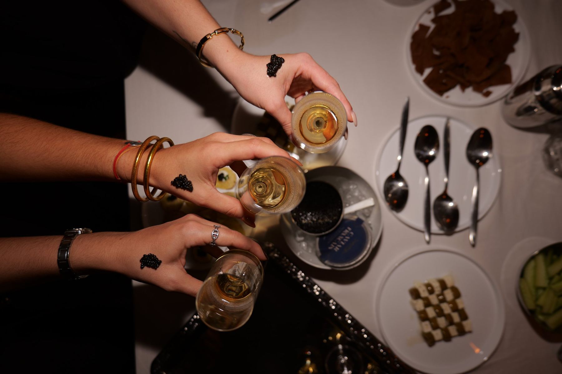 Invités dégustant le caviar à la russe sur le dos de la main, coupe de champagne en main